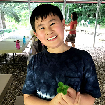Boy with four-leaf clover at Earthaven Ecovillage