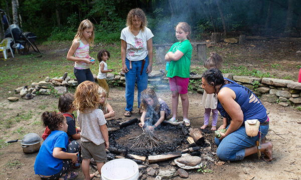 A girl learning to build a fire in the Compassion Camp kids' program