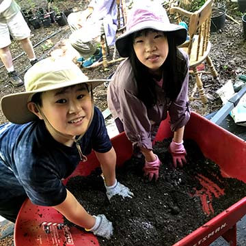 Children preparing soil to pot nursery plants