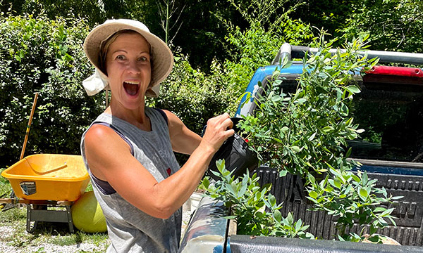 photo of a happy woman removing a plant from a truck